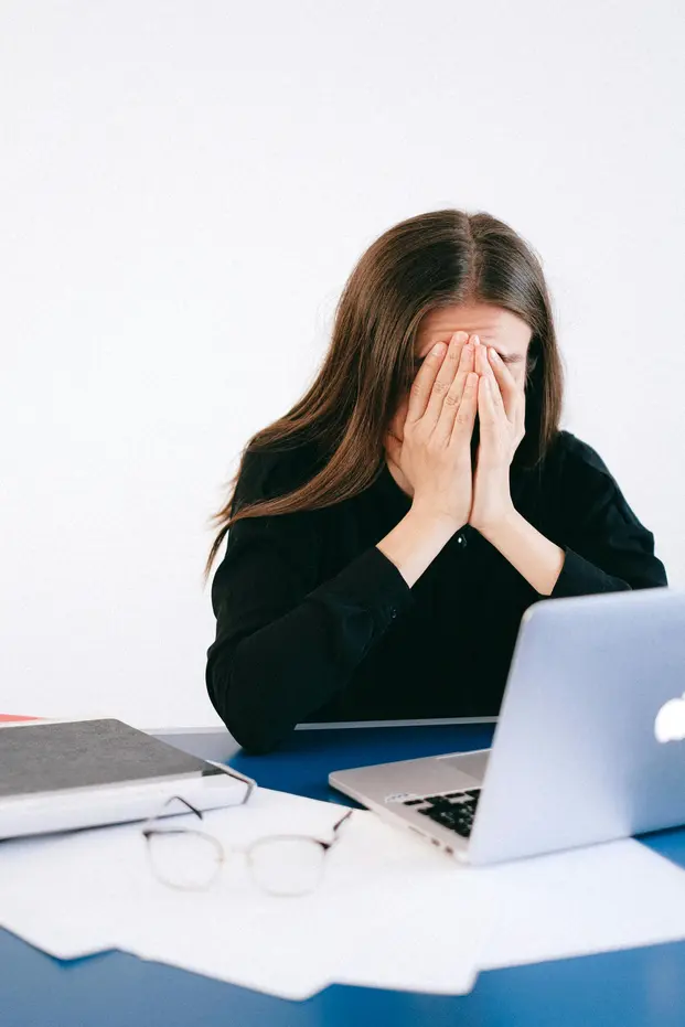 Professionista esausta alla scrivania: il burnout lavorativo come segnale di un sistema fragile che necessita di robustezza sostenibile